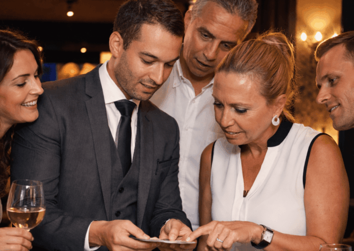 vinz magicien faisant un tour de carte devant un public d'hommes et de femmes